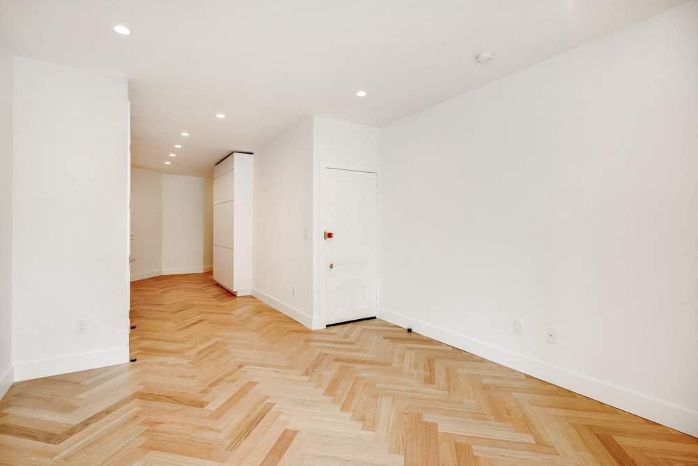 a renovated living room with a wooden floor and white walls